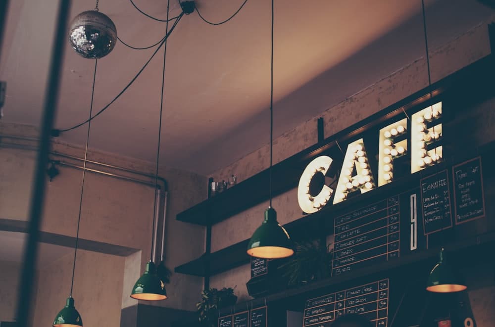 Papan bertuliskan CAFE di dinding gelap dengan lampu gantung