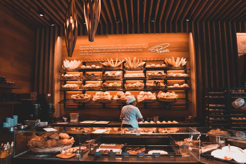 Konter kedai dengan pencahayaan hangat dan deretan roti
